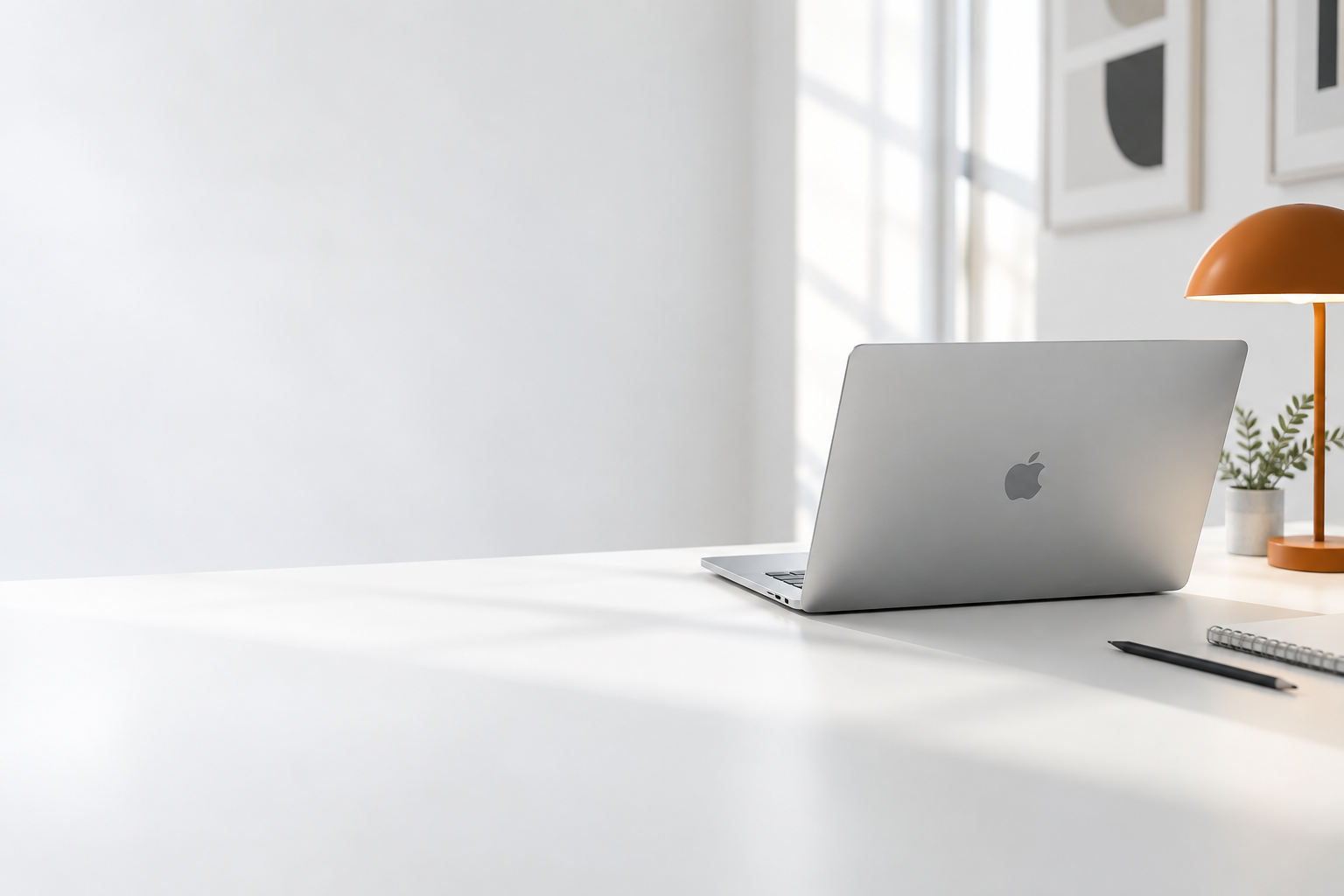 Mesa de criação com MacBook prateado e luminária laranja